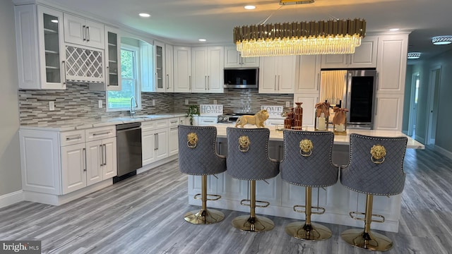 104 Lake Front Dr, Dover, DE 19904 - kitchen with stainless steel appliances, white cabinets, light wood-type flooring, a center island, and backsplash
