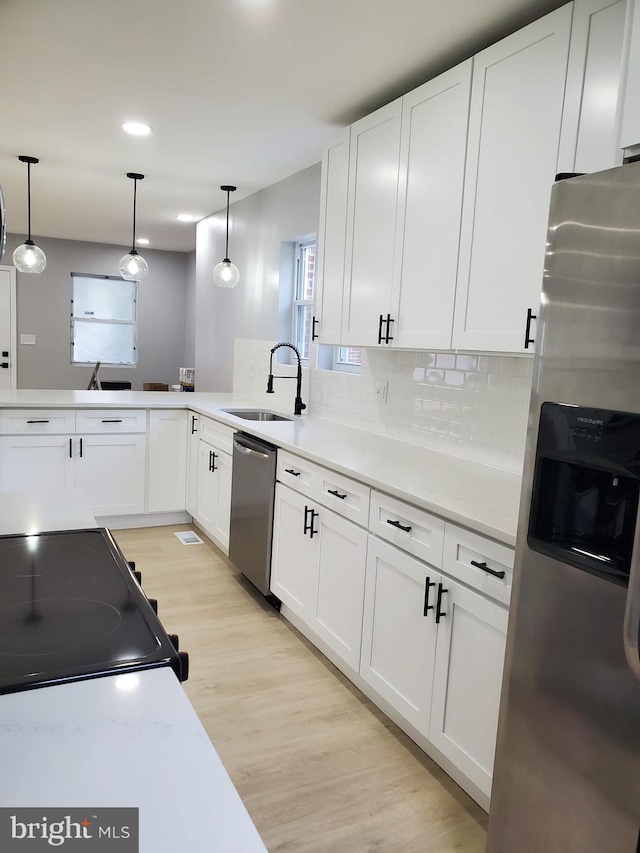 2011 Englewood Ave, Baltimore, MD 21207 - kitchen with stainless steel appliances, light wood-type flooring, decorative backsplash, white cabinets, and recessed lighting