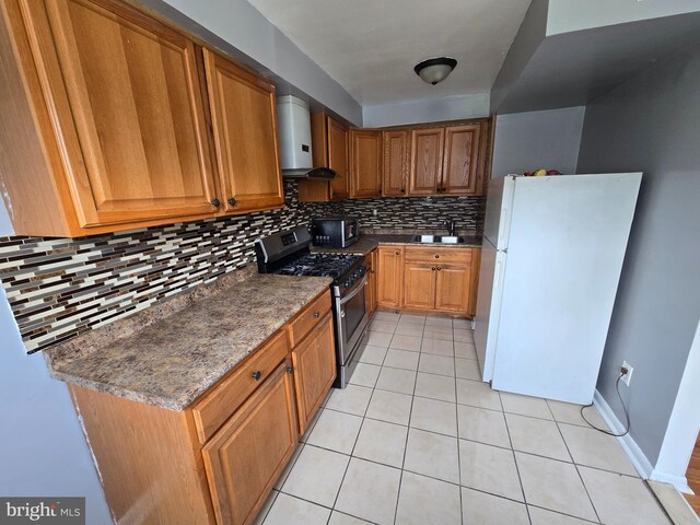 5903 Algon Ave, Philadelphia, PA 19149 - kitchen featuring freestanding refrigerator, stainless steel range with gas cooktop, wall chimney range hood, tasteful backsplash, and brown cabinets