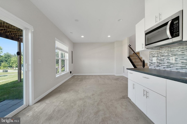 42510 Oak Park Sq, Ashburn, VA 20148 - kitchen featuring stainless steel microwave, light colored carpet, tasteful backsplash, dark countertops, and white cabinetry