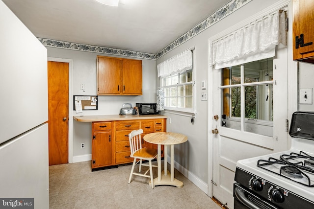 73 Duncan Ln, Springfield, PA 19064 - kitchen featuring gas range oven, freestanding refrigerator, brown cabinets, and light countertops