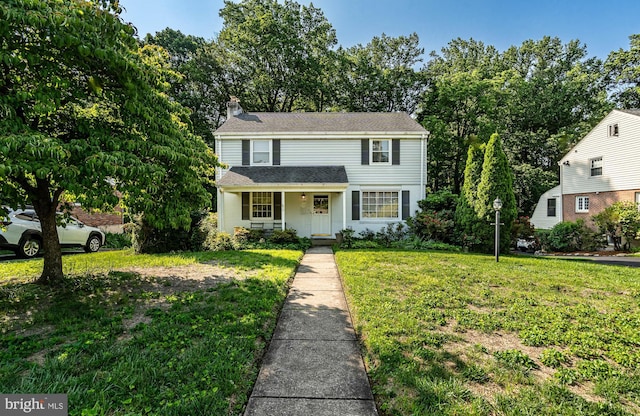 73 Duncan Ln, Springfield, PA 19064 - traditional-style house with a front yard, a chimney, a porch, a shingled roof, and view of scattered trees