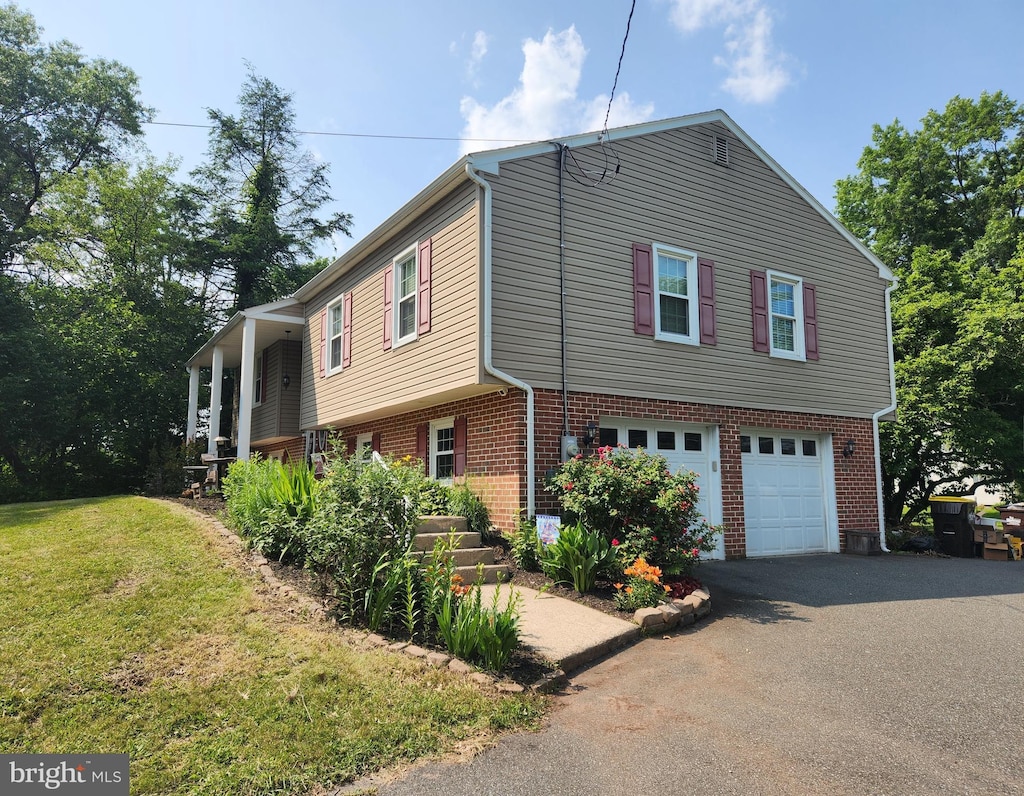 295 E Moyer Rd, Pottstown, PA 19464 - view of property exterior with a garage, asphalt driveway, brick siding, and a yard