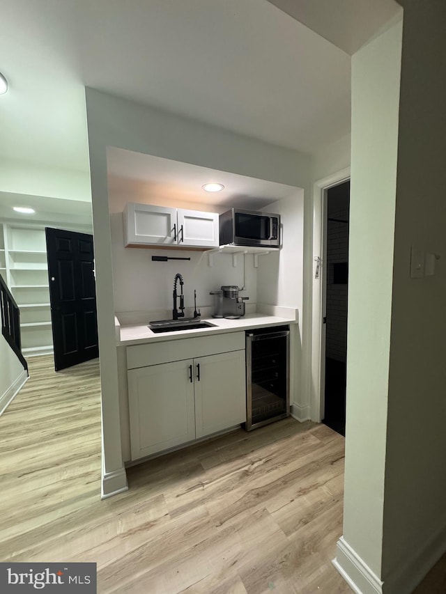 6529 Frietchie Row, Columbia, MD 21045 - kitchen featuring beverage cooler, stainless steel microwave, light wood-style flooring, light countertops, and white cabinetry