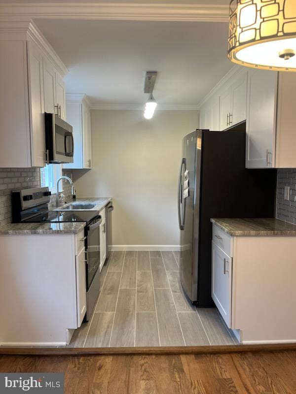 5511 Wesley Ave, Baltimore, MD 21207 - kitchen featuring stainless steel appliances, light wood-style floors, backsplash, white cabinets, and ornamental molding