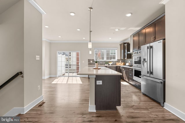 7955 Blue Stream Dr, Elkridge, MD 21075 - kitchen with stainless steel appliances, ornamental molding, dark brown cabinetry, tasteful backsplash, and light countertops