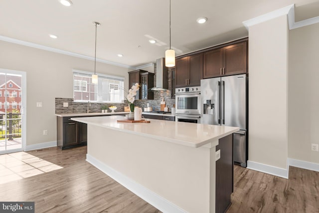 7955 Blue Stream Dr, Elkridge, MD 21075 - kitchen with stainless steel appliances, ornamental molding, dark brown cabinets, wall chimney range hood, and backsplash