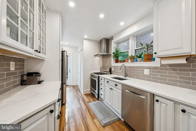 636 N Alfred St, Alexandria, VA 22314 - kitchen with appliances with stainless steel finishes, wall chimney range hood, decorative backsplash, white cabinetry, and recessed lighting