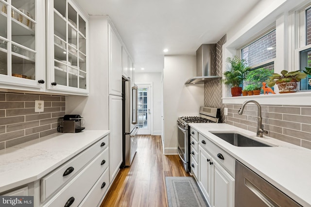 636 N Alfred St, Alexandria, VA 22314 - kitchen with stainless steel appliances, wall chimney exhaust hood, wood finished floors, white cabinetry, and decorative backsplash
