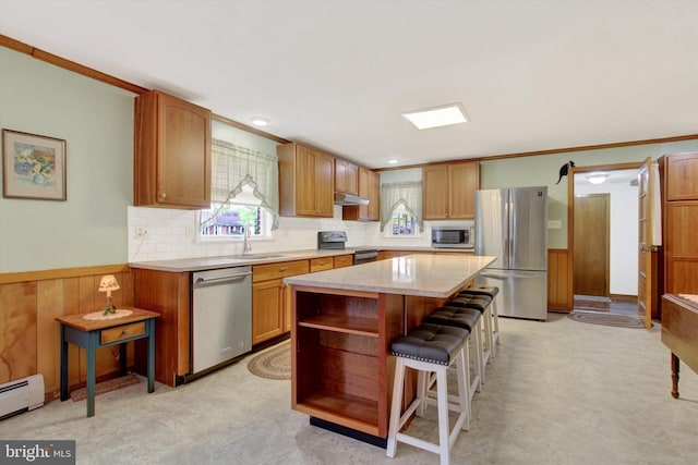 401 Jacobs St, East Berlin, PA 17316 - kitchen with stainless steel appliances, baseboard heating, under cabinet range hood, tasteful backsplash, and a kitchen breakfast bar