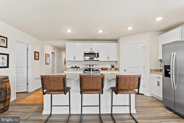 9 American Ave, Carlisle, PA 17013 - kitchen featuring stainless steel appliances, light wood finished floors, white cabinetry, a kitchen breakfast bar, and recessed lighting