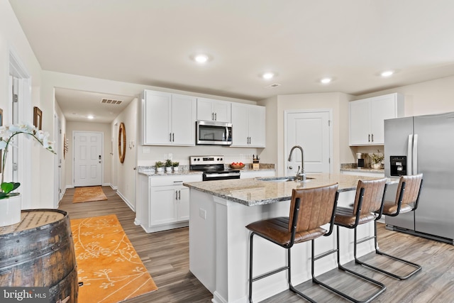 9 American Ave, Carlisle, PA 17013 - kitchen with stainless steel appliances, light wood-style flooring, white cabinets, a breakfast bar, and a center island with sink