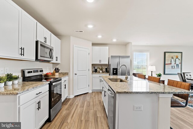 9 American Ave, Carlisle, PA 17013 - kitchen with appliances with stainless steel finishes, light wood-type flooring, a kitchen bar, a kitchen island with sink, and white cabinetry