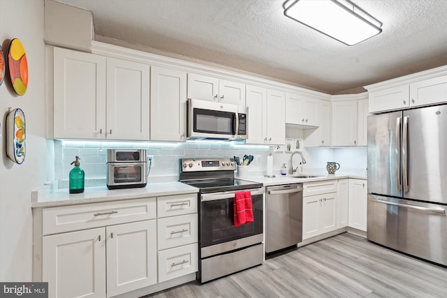 8370 Greensboro Dr Unit 1011, Mclean, VA 22102 - kitchen featuring stainless steel appliances, white cabinetry, light wood-type flooring, backsplash, and a textured ceiling