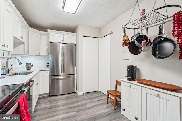 8370 Greensboro Dr Unit 1011, Mclean, VA 22102 - kitchen featuring stainless steel appliances, a textured ceiling, light wood-style floors, white cabinets, and light countertops