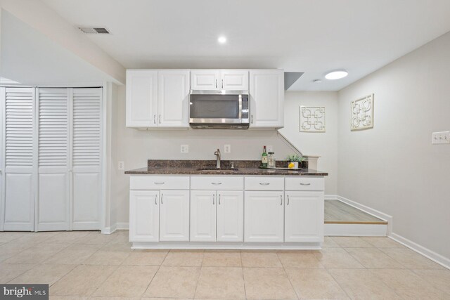 17105 Amity Dr, Derwood, MD 20855 - kitchen featuring stainless steel microwave, white cabinets, dark stone counters, light tile patterned floors, and recessed lighting