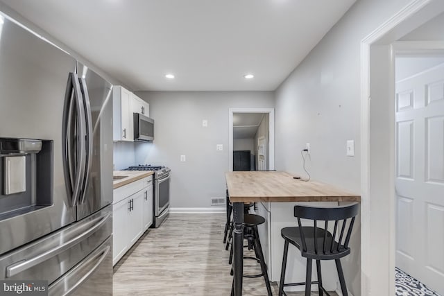 7135 Railway, Dundalk, MD 21222 - kitchen with stainless steel appliances, butcher block countertops, a breakfast bar, white cabinets, and recessed lighting