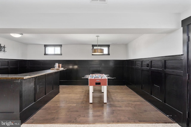 115 Saddle Ridge Ln, Fredericksburg, VA 22406 - kitchen with dark cabinetry, wood finished floors, wainscoting, a decorative wall, and hanging light fixtures