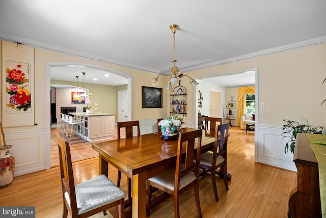 9100 Quarter Ct, Vienna, VA 22182 - dining room featuring light wood-style flooring, ornamental molding, a decorative wall, wainscoting, and arched walkways