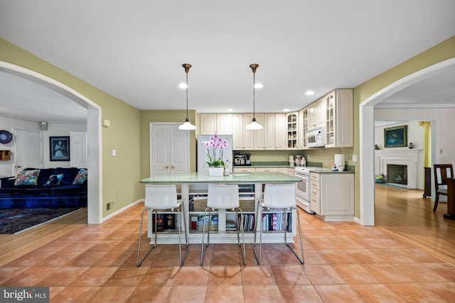 9100 Quarter Ct, Vienna, VA 22182 - kitchen with white appliances, a kitchen island, glass insert cabinets, decorative light fixtures, and light countertops