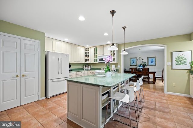 9100 Quarter Ct, Vienna, VA 22182 - kitchen with white appliances, a kitchen bar, a kitchen island, arched walkways, and light stone countertops