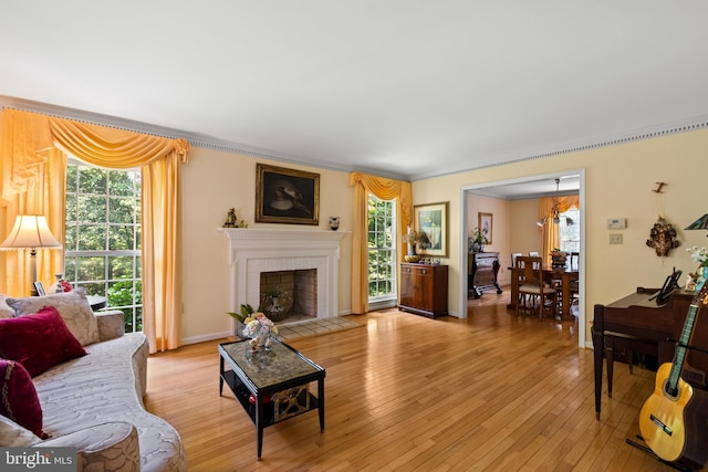 9100 Quarter Ct, Vienna, VA 22182 - living room featuring healthy amount of natural light, light wood-style floors, a chandelier, a brick fireplace, and crown molding