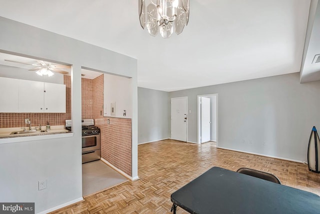 7054 Eastern Ave NW Unit 103, Washington, DC 20012 - kitchen featuring gas stove, white cabinetry, decorative backsplash, ceiling fan, and light countertops