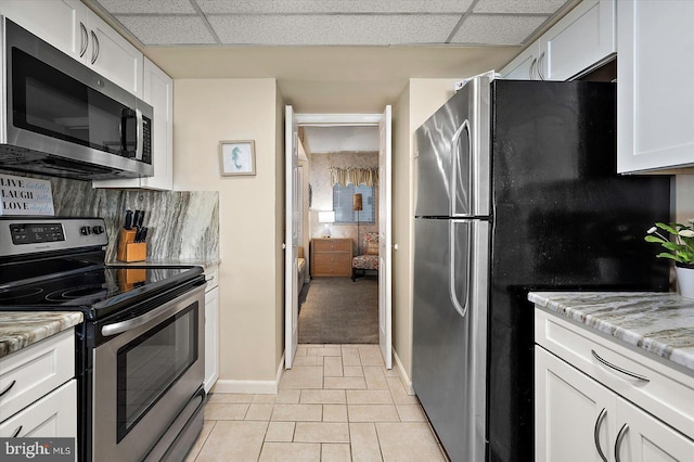 9800 Coastal Hwy Unit 1207, Ocean City, MD 21842 - kitchen with stainless steel appliances, a drop ceiling, white cabinetry, light tile patterned floors, and light stone counters