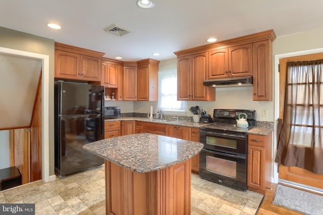 1002 S 2nd Ave, Lebanon, PA 17042 - kitchen featuring black appliances, under cabinet range hood, light stone counters, brown cabinetry, and stone finish floors