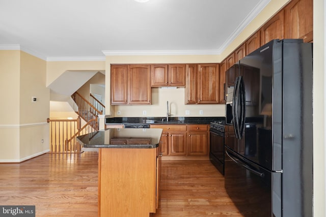 8078 Horseshoe Cottage Cir, Lorton, VA 22079 - kitchen featuring black appliances, ornamental molding, light wood finished floors, a center island, and brown cabinetry