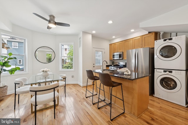 643 Keefer Pl NW, Washington, DC 20010 - kitchen featuring appliances with stainless steel finishes, stacked washer and clothes dryer, a kitchen breakfast bar, light wood-style floors, and a ceiling fan