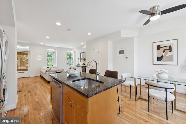 643 Keefer Pl NW, Washington, DC 20010 - kitchen featuring stacked washer and clothes dryer, dishwasher, light wood-style floors, a kitchen island with sink, and a kitchen breakfast bar