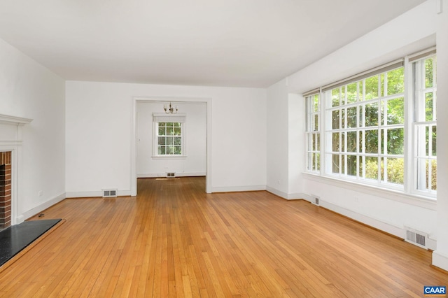 906 Old Farm Rd, Charlottesville, VA 22903 - unfurnished living room with a brick fireplace, light wood finished floors, and a chandelier