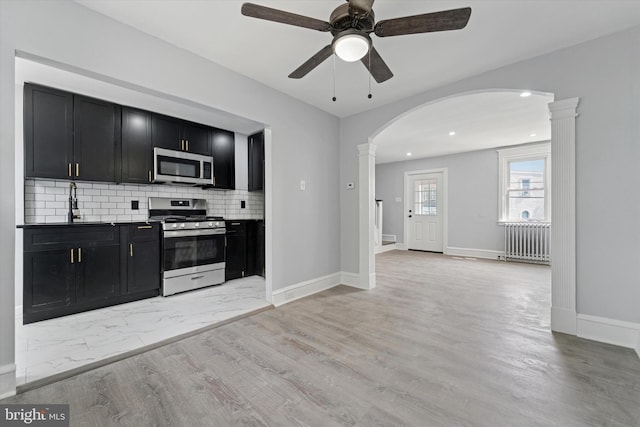 7139 Guilford Rd, Upper Darby, PA 19082 - kitchen featuring appliances with stainless steel finishes, dark cabinets, radiator, arched walkways, and ceiling fan
