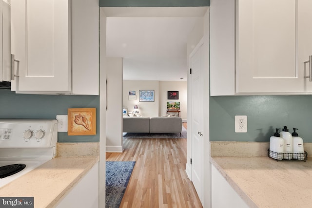 317 10th St NE Unit 13, Washington, DC 20002 - kitchen with range, white cabinets, light wood-style floors, and light stone countertops