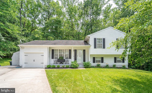 7781 Monaghan Rd, Glen Burnie, MD 21060 - tri-level home featuring an attached garage, driveway, a front lawn, a porch, and view of wooded area