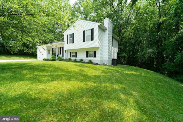 7781 Monaghan Rd, Glen Burnie, MD 21060 - tri-level home featuring a chimney, a front lawn, an attached garage, and view of wooded area