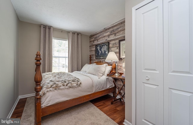 7781 Monaghan Rd, Glen Burnie, MD 21060 - bedroom featuring dark wood-style floors, a textured ceiling, wood walls, and an accent wall