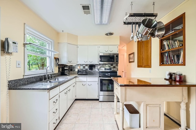 12105 Lanham Severn Rd, Bowie, MD 20720 - kitchen with stainless steel appliances, backsplash, white cabinetry, light tile patterned floors, and dark stone counters