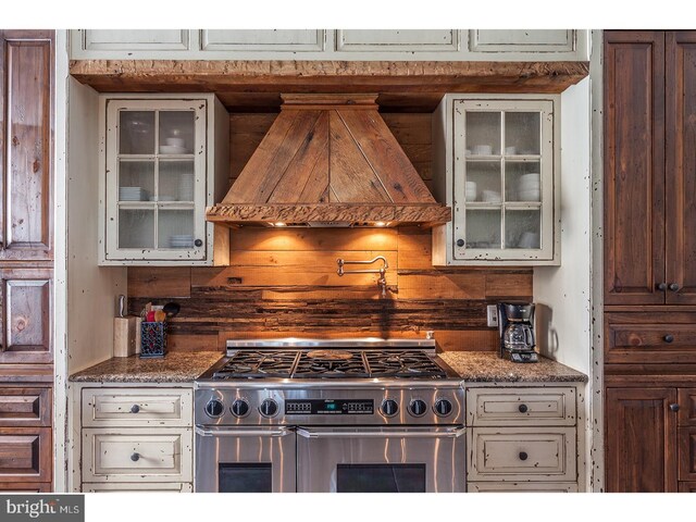 2103 Street Rd, New Hope, PA 18938 - kitchen with range with two ovens, custom range hood, glass insert cabinets, and decorative backsplash