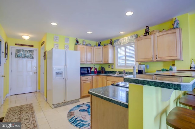 6180 Marsh Island Dr, Chincoteague Island, VA 23336 - kitchen featuring white refrigerator with ice dispenser, light brown cabinets, a breakfast bar, dark countertops, and recessed lighting