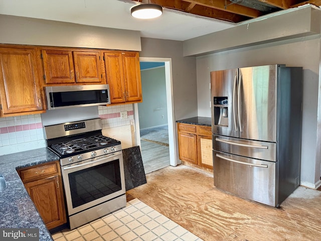 2575 Romig Rd, Gilbertsville, PA 19525 - kitchen with appliances with stainless steel finishes, brown cabinets, tasteful backsplash, and dark stone countertops