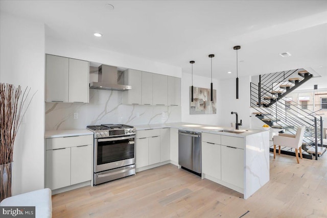 2618 E Hagert St, Philadelphia, PA 19125 - kitchen featuring stainless steel appliances, wall chimney range hood, modern cabinets, light wood-style floors, and backsplash