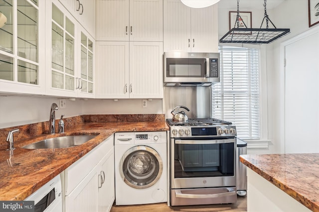 3042 R St NW Unit 2, Washington, DC 20007 - kitchen with washer / dryer, stainless steel appliances, white cabinetry, dark stone counters, and glass insert cabinets