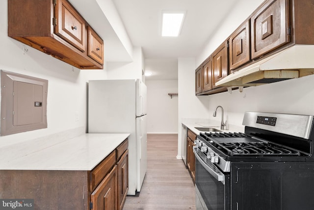 3378 Woodburn Rd Unit 11, Annandale, VA 22003 - kitchen with gas range, electric panel, freestanding refrigerator, light wood-style flooring, and under cabinet range hood