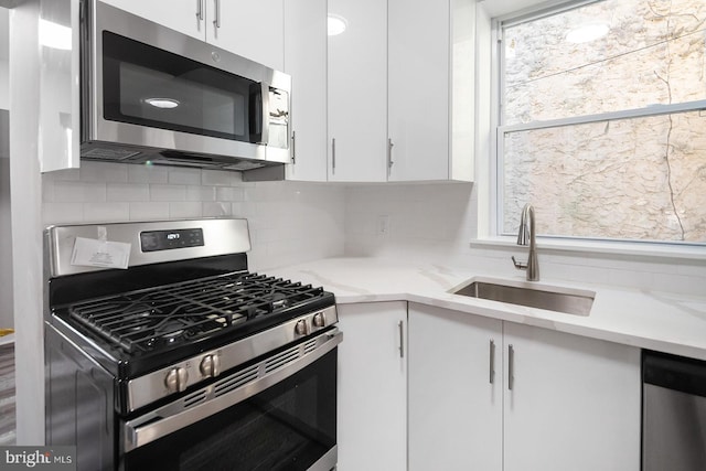 2332 N 25th St, Philadelphia, PA 19132 - kitchen featuring appliances with stainless steel finishes, white cabinetry, light stone counters, and decorative backsplash