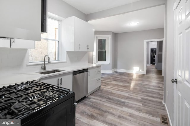 2332 N 25th St, Philadelphia, PA 19132 - kitchen featuring stainless steel dishwasher, range with gas cooktop, white cabinetry, light wood finished floors, and light countertops