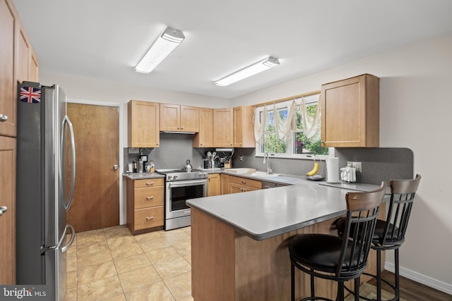 724 Franklinville Rd, Mullica Hill, NJ 08062 - kitchen featuring appliances with stainless steel finishes, a peninsula, light brown cabinetry, and a kitchen breakfast bar