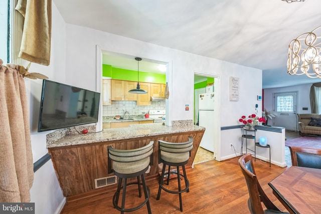 712 Chesapeake St SE, Washington, DC 20032 - kitchen with white appliances, wood finished floors, tasteful backsplash, under cabinet range hood, and a peninsula