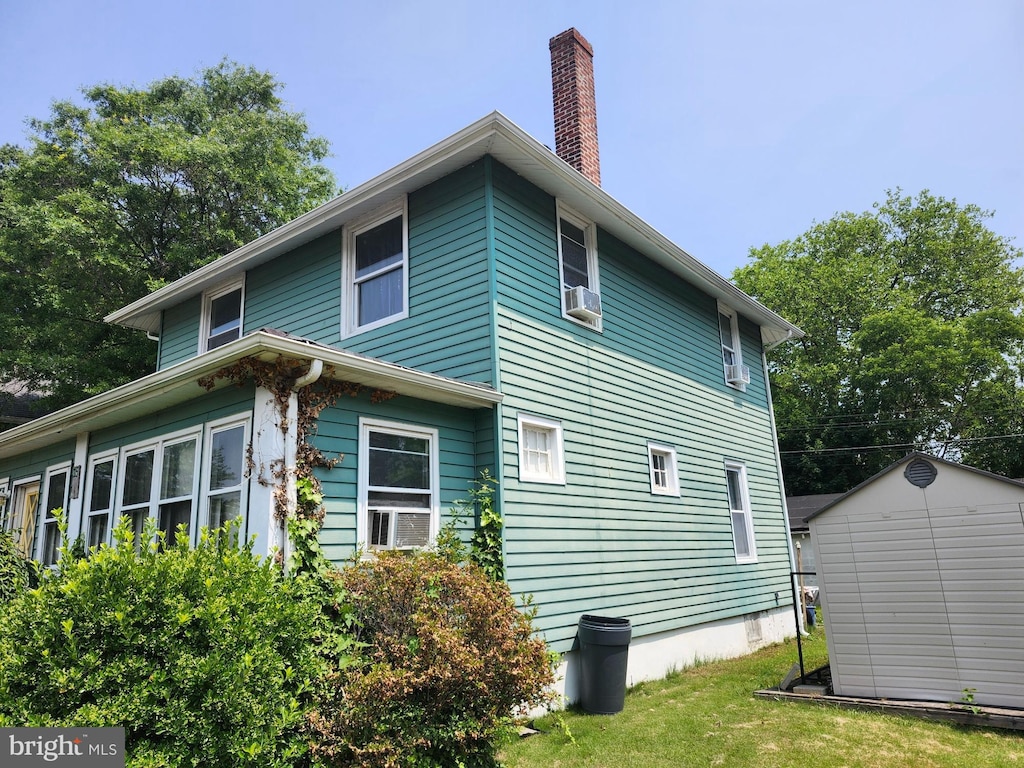 15 Spring St, Penns Grove, NJ 08069 - view of side of home with a shed, a chimney, cooling unit, and a lawn